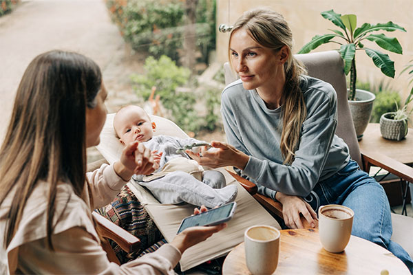 Two,Women,Talking,In,A,Cafe.,Mother,With,Baby.